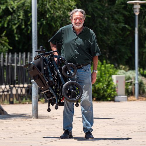 Persona transportando la silla de ruedas eléctrica iVolta plegada