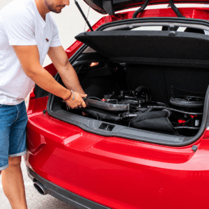 Persona colocando la silla eléctrica Martinika Carbon Evo plegada en el maletero de un coche rojo