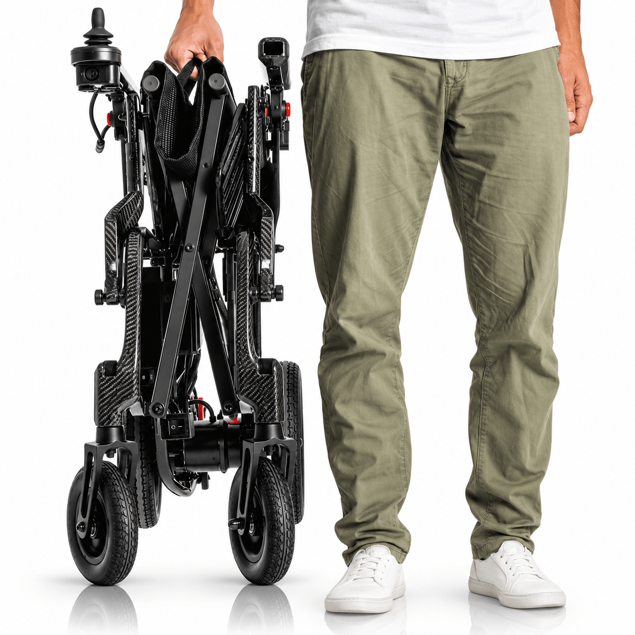 Persona sujetando la silla eléctrica Martinika Carbon Evo plegada junto a su cuerpo para mostrar su tamaño compacto